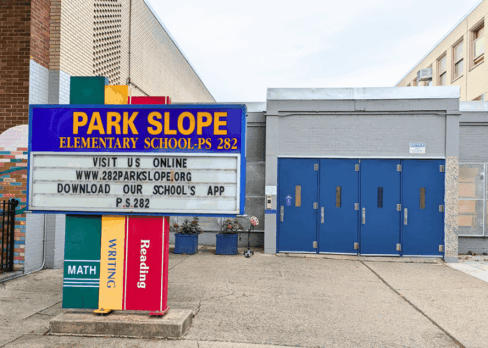 Picture of blue doors entrance to PS 282 with a sign in front that reads "Park Slope Elementary School PS 282 Visit us online"