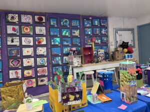Colorful artwork displayed in a grid-like pattern on a classroom wall