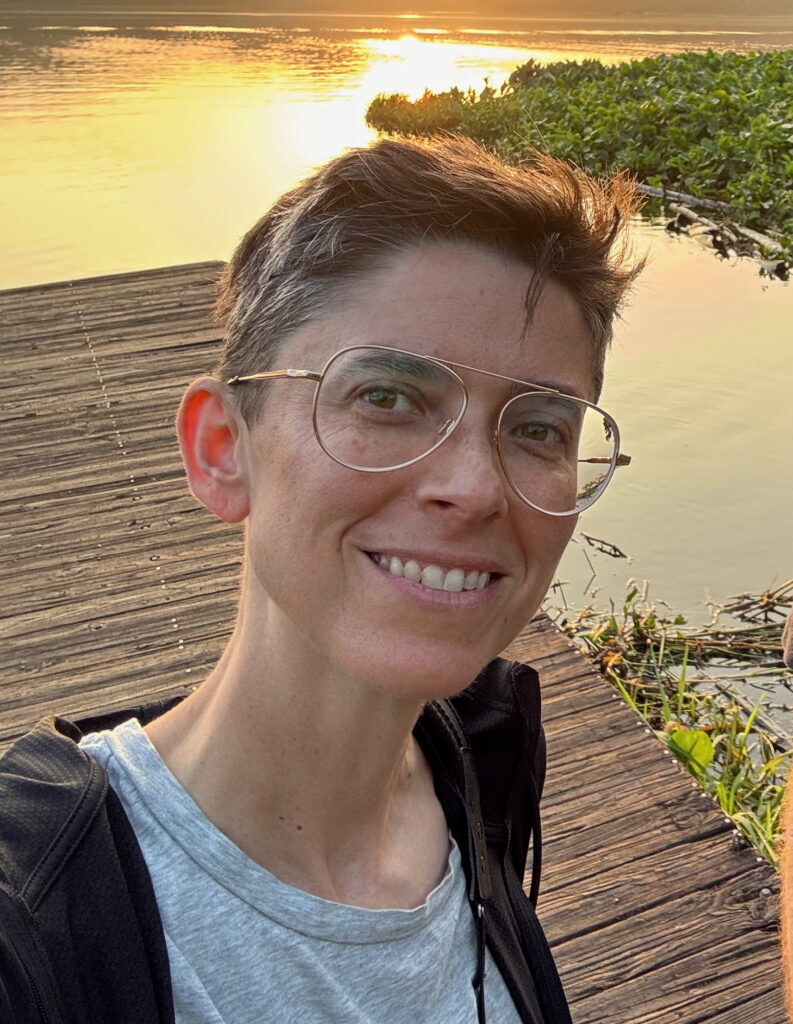 Julie Hollar smiles outside, standing on a dock