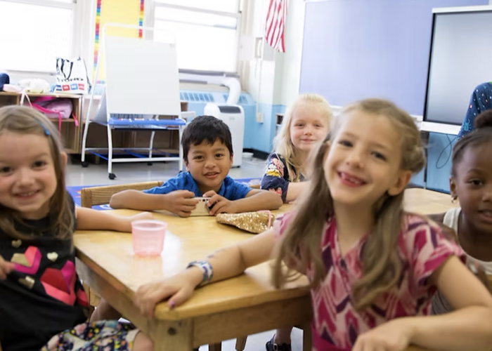Children sitting in a sunny classroom, smiling