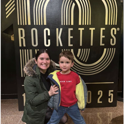 Mom next to child standing in front of a Rockettes sign. 